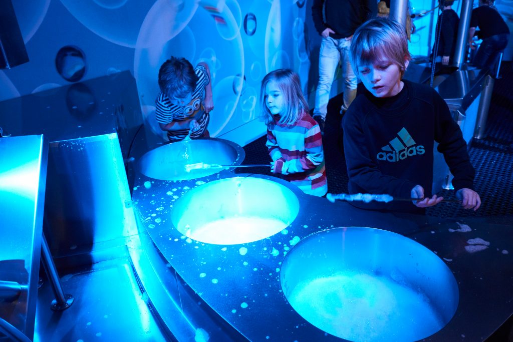 tri deti hrajúce sa centre vedy a techniky v zážitkovom centre