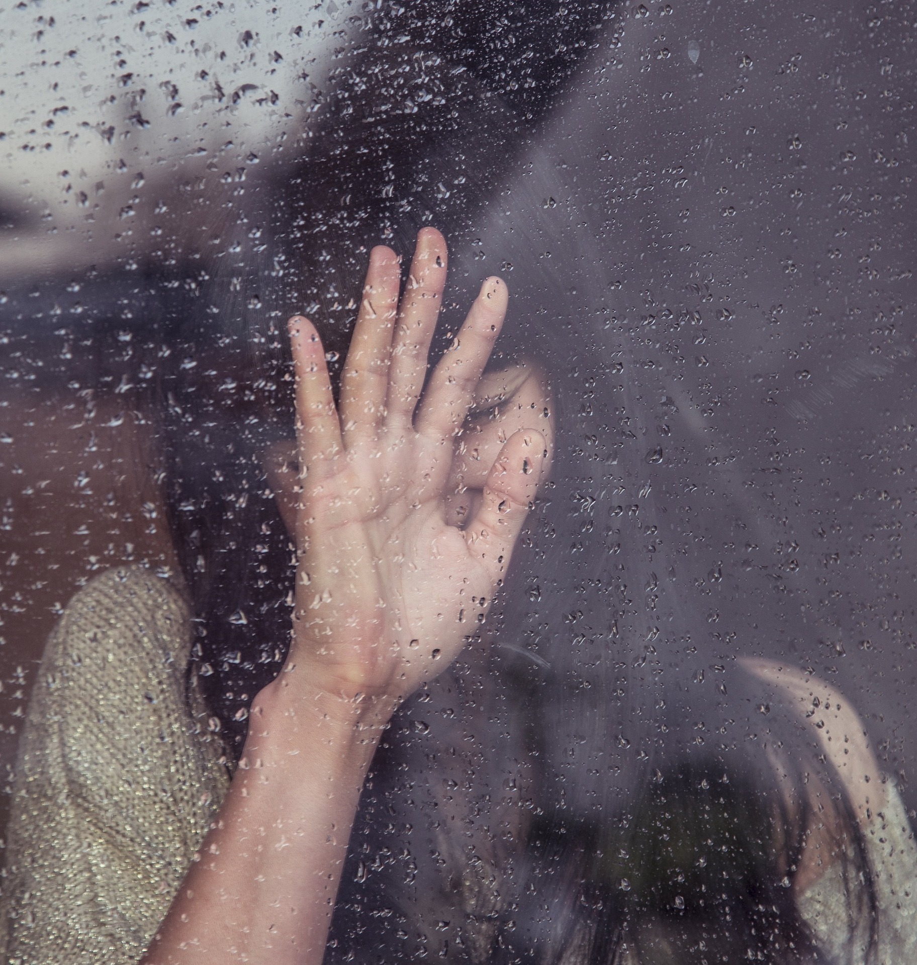 mladé dievča stojace za zaroseným oknom