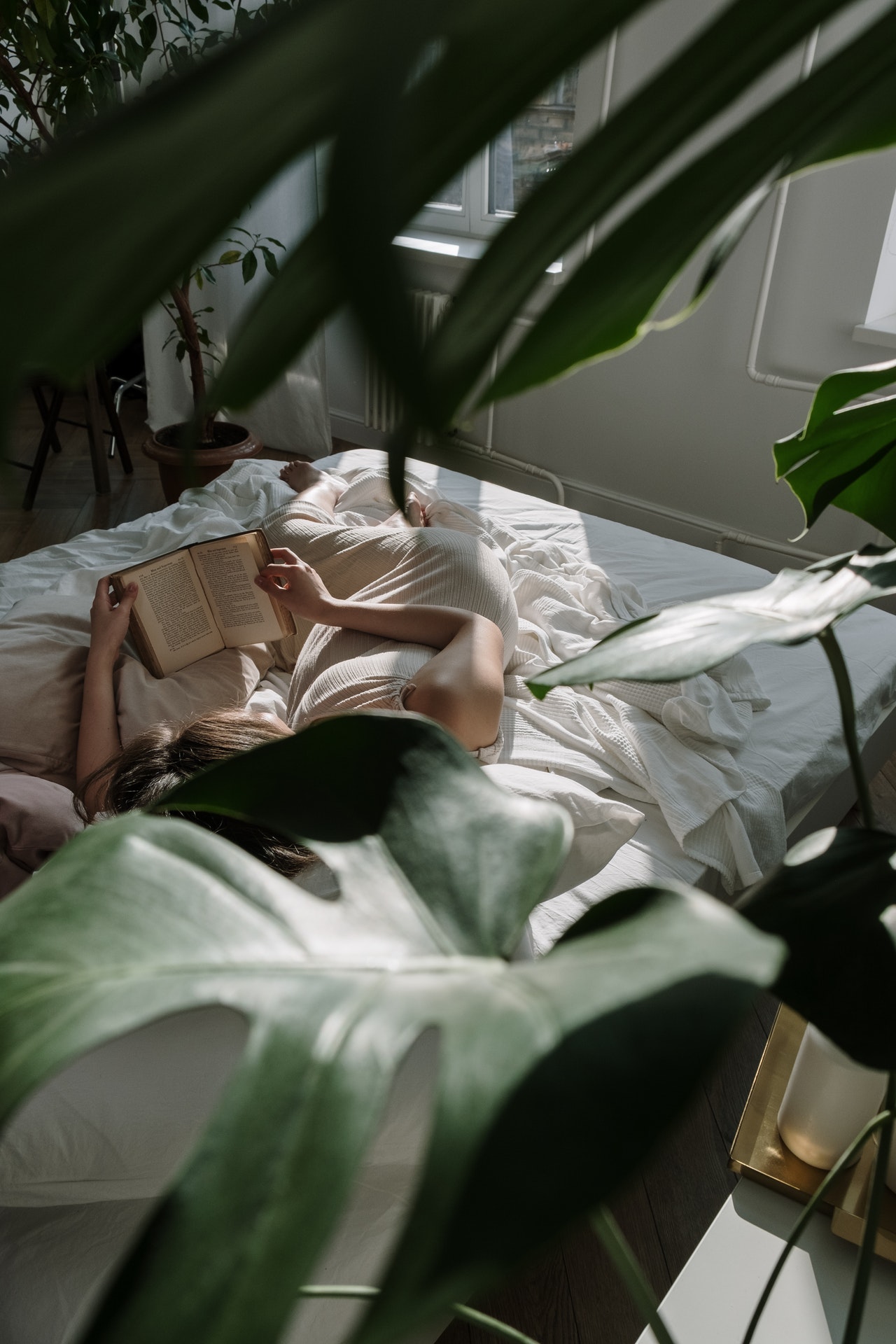 krásna mladá žena ležiaca v posteli vo svojom byte dizajnovanom v urban jungle štýle
