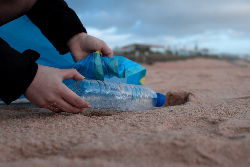 mladá žena zbierajúca odpad a plast na pláži