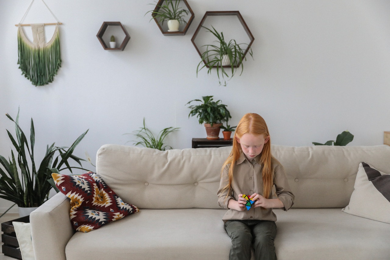ryšavé dievčatko sediace na gauči v modernom interiéri zariadenom v roku 2020