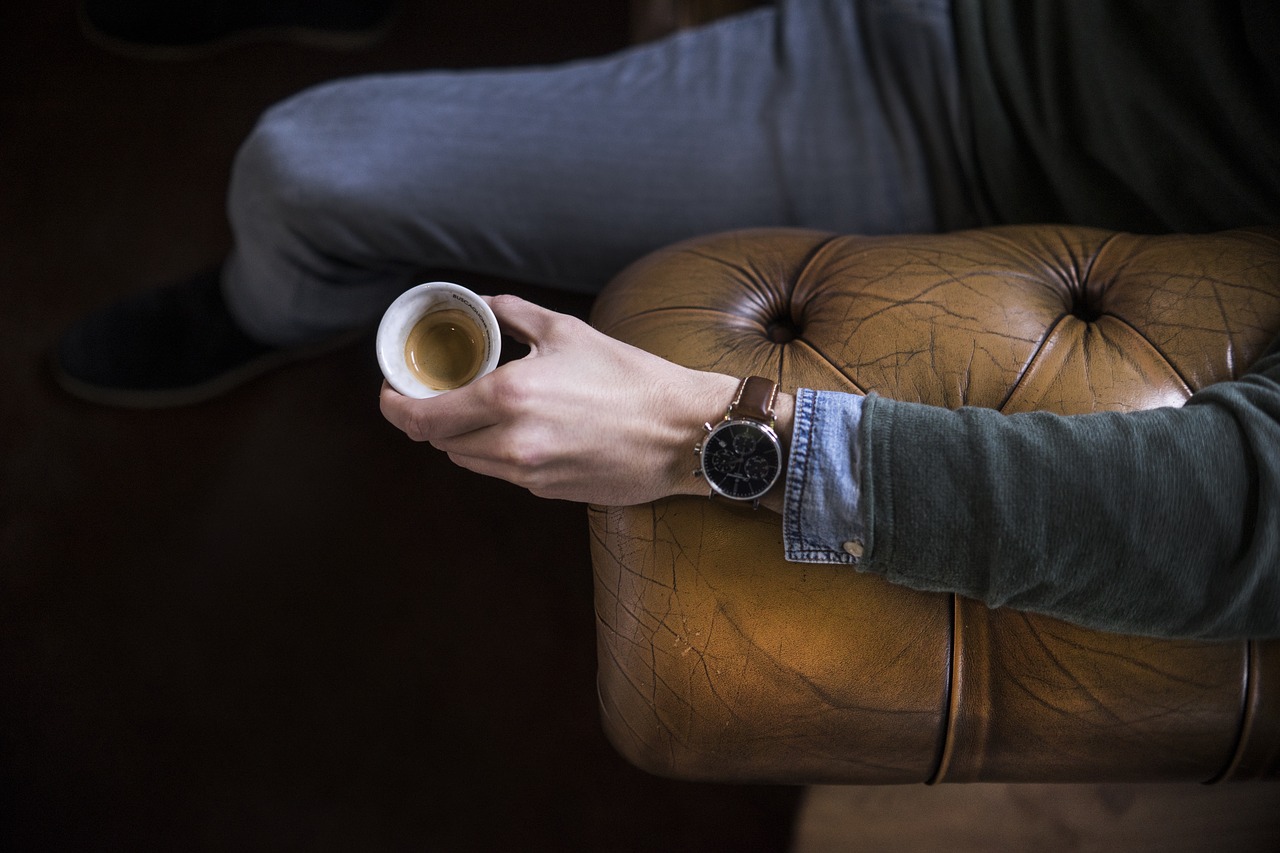 muž sediaci na pohovke chesterfield s kávou v ruke