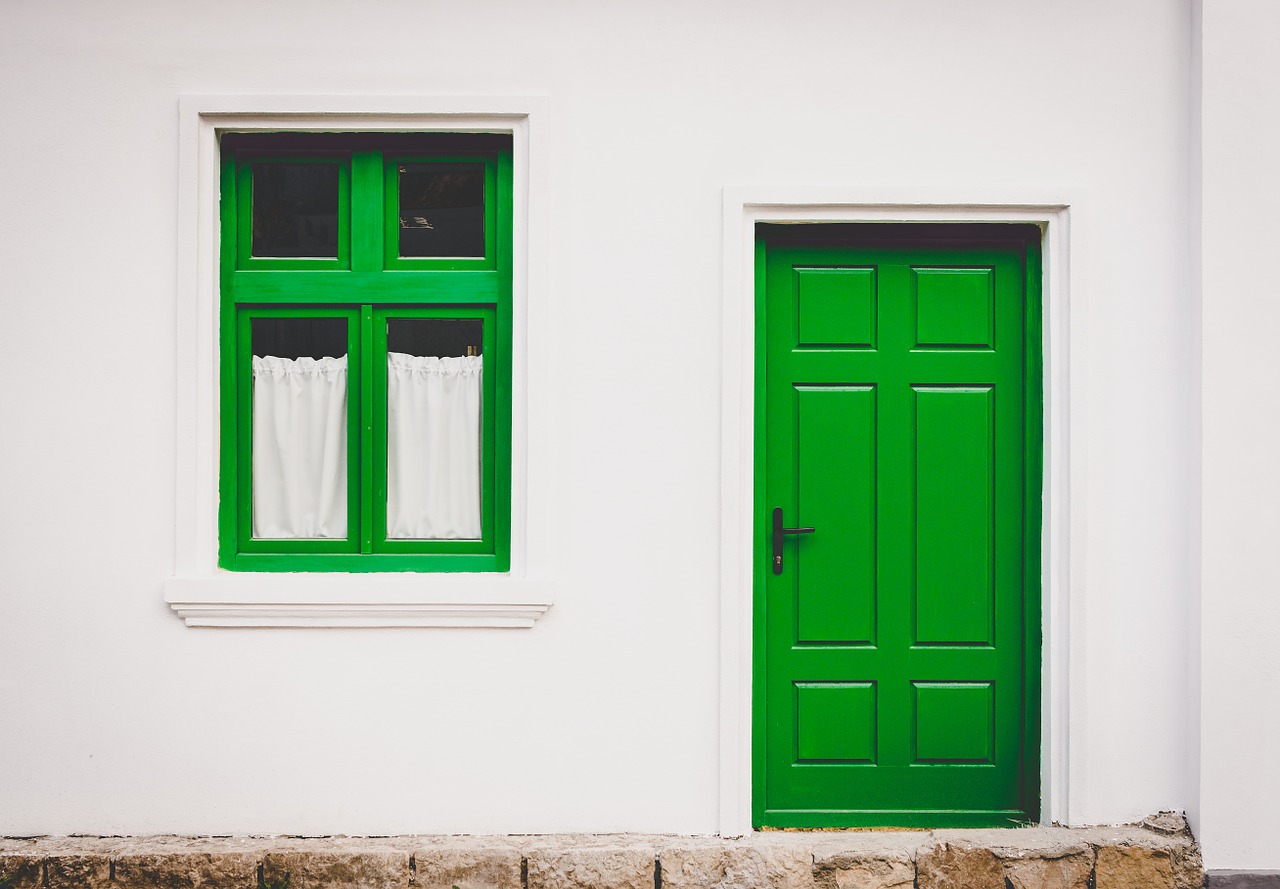 čerstvo vymaľovaná fasáda domu so zelenými dverami a oknom