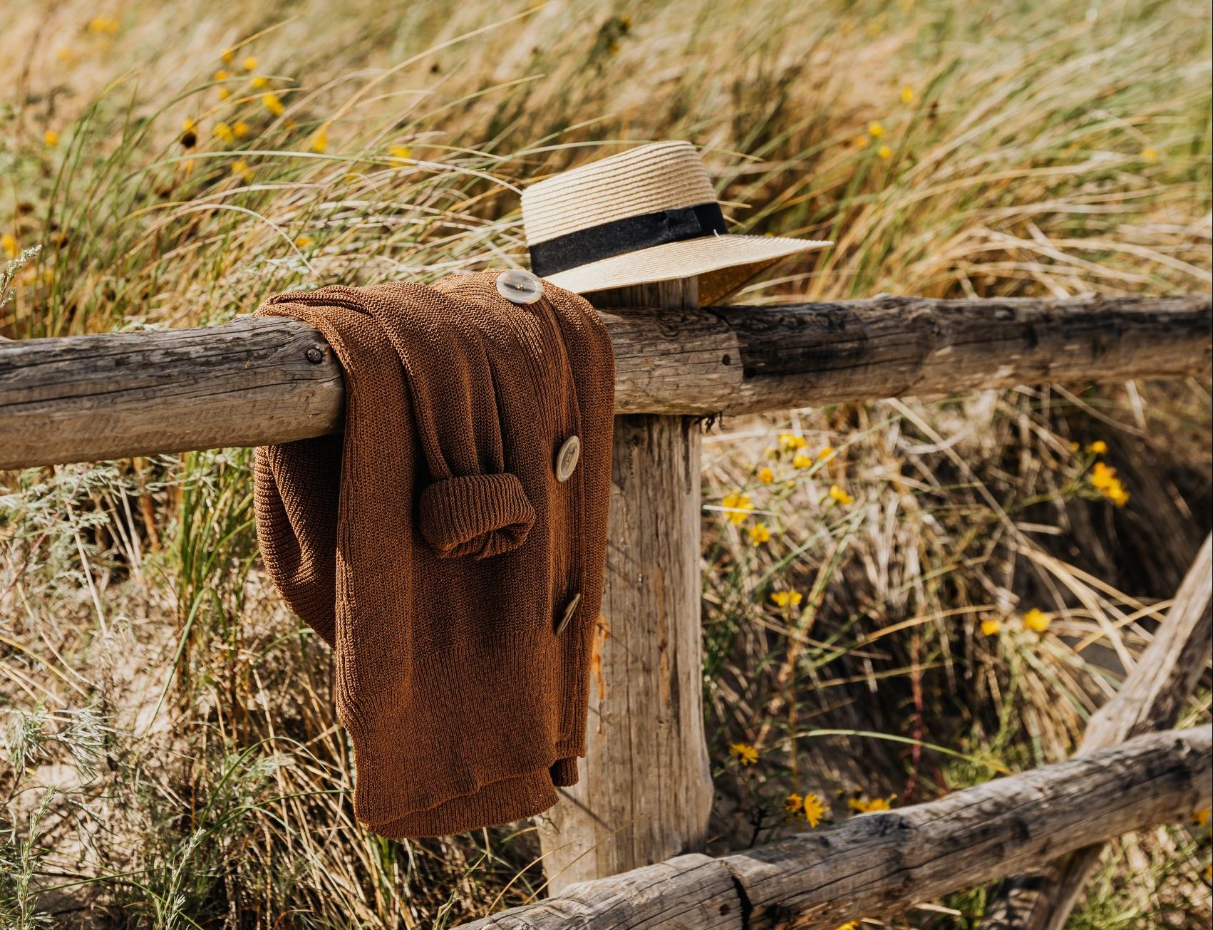 Klobúk a sveter prevesený cez drevený plot
